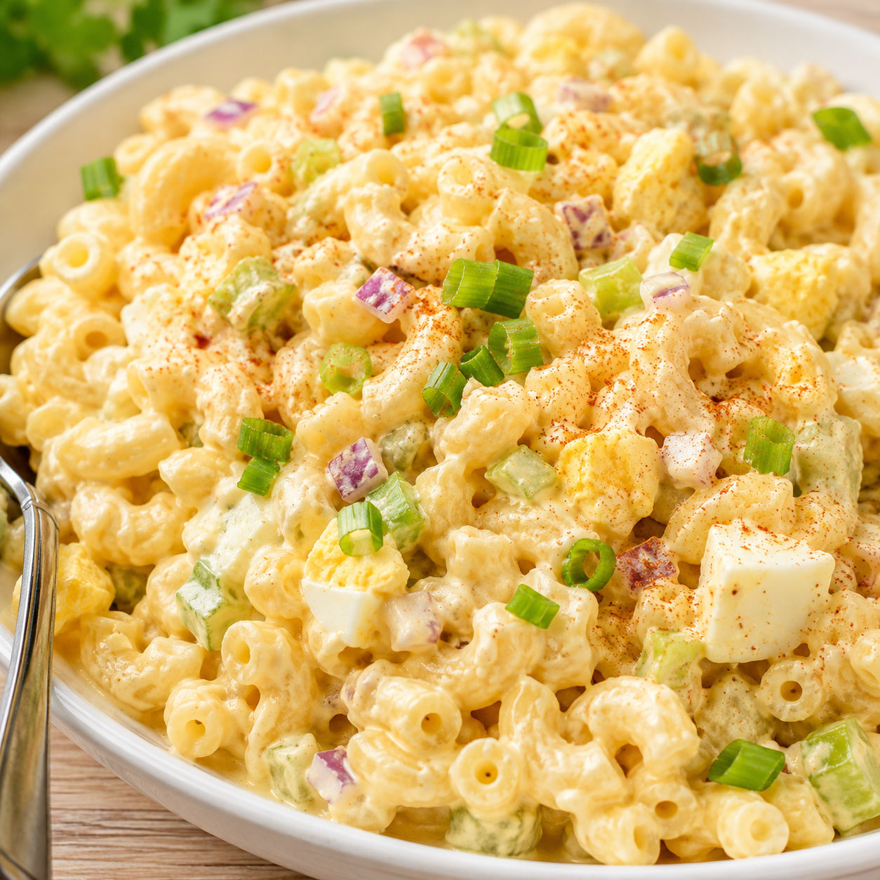 Deviled egg pasta salad with green onion and smoked paprika in a white bowl