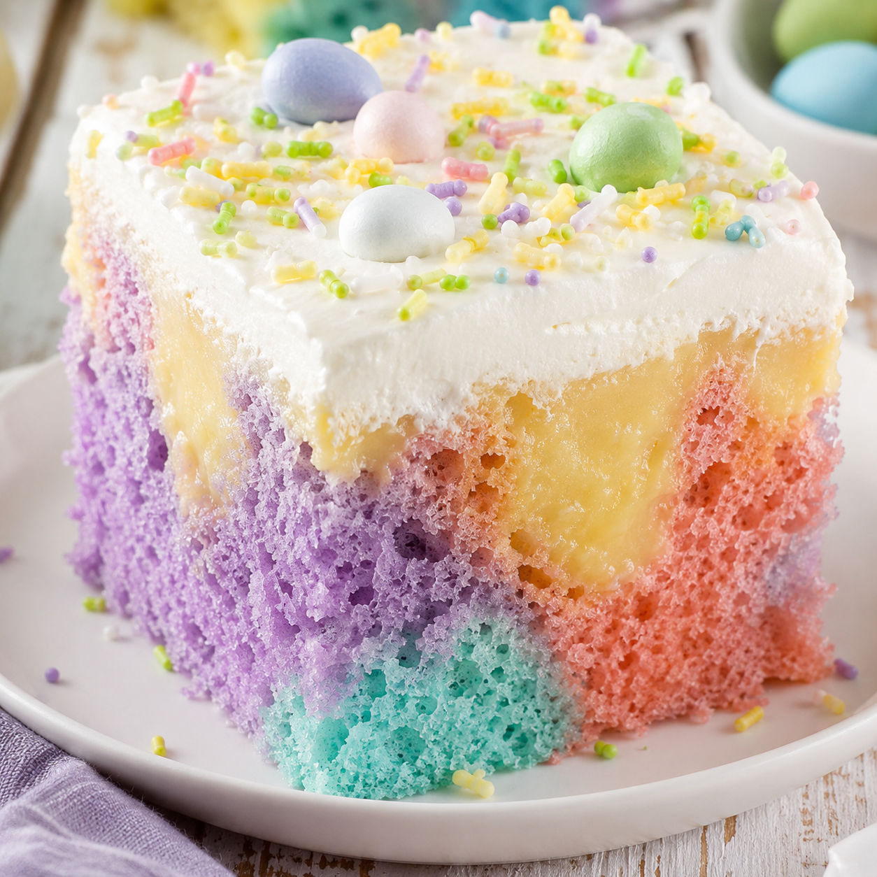 Pastel Easter poke cake slice with whipped topping and sprinkles