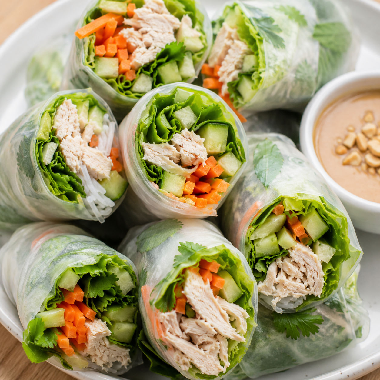 Chicken spring rolls with vegetables, herbs, and peanut dipping sauce