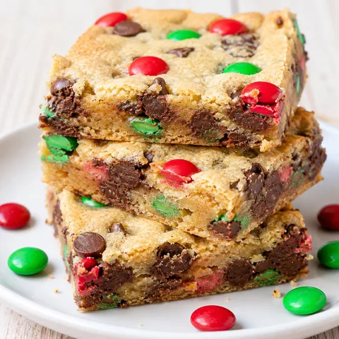 M&M cookie bars stacked on a plate with chocolate chips