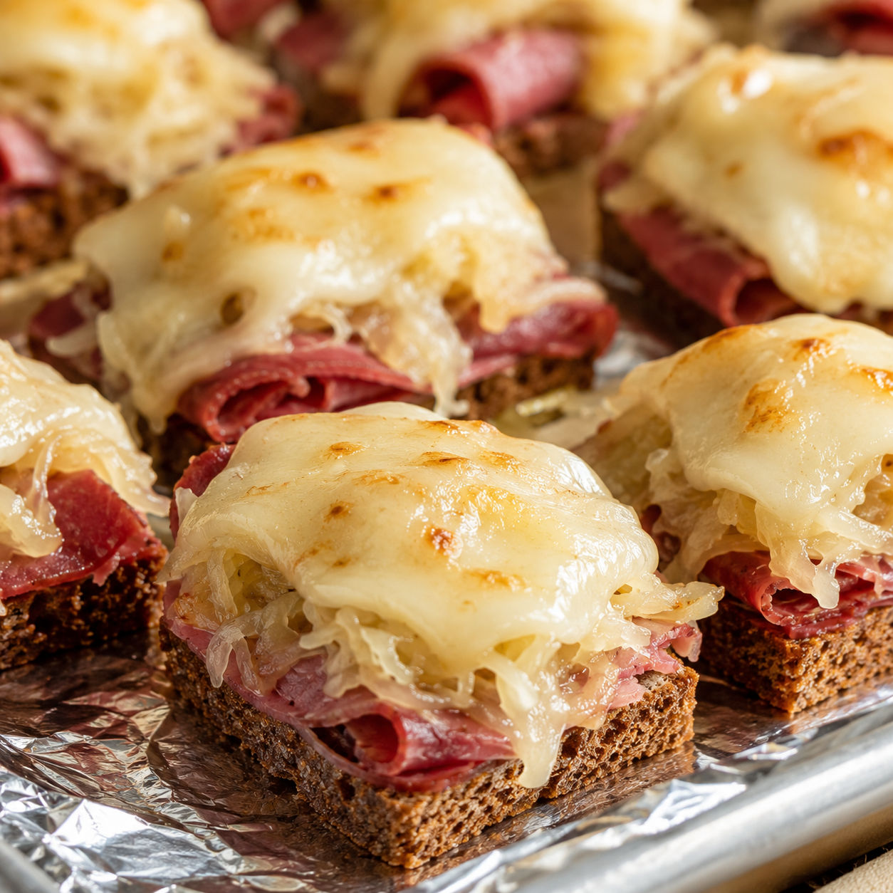 Baked mini Reuben bites with melted Swiss on cocktail rye
