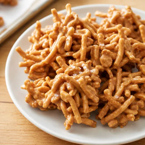 Butterscotch haystacks with chow mein noodles and peanuts on a white plate