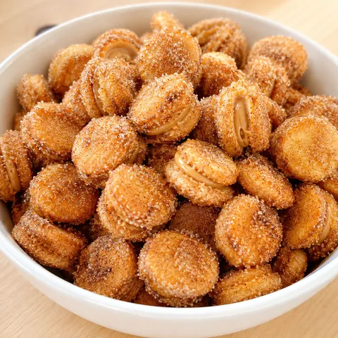 Golden Ritz churro bites coated in cinnamon sugar piled in a white bowl