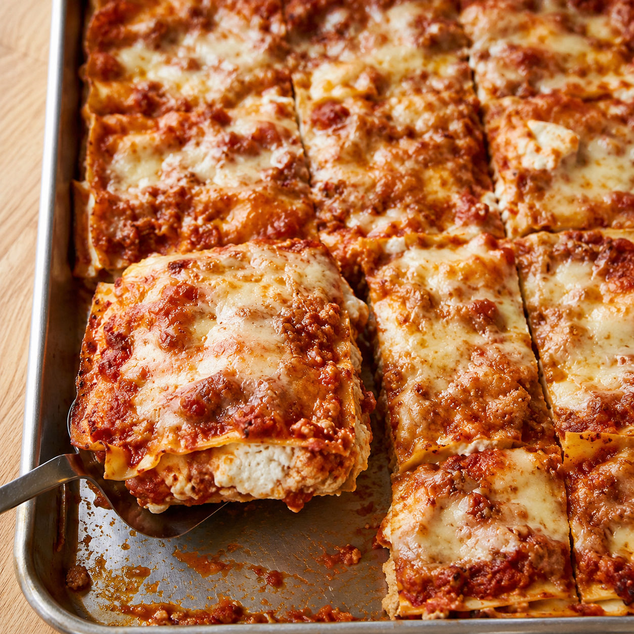 Sheet pan lasagna with browned cheese and parsley on a metal pan