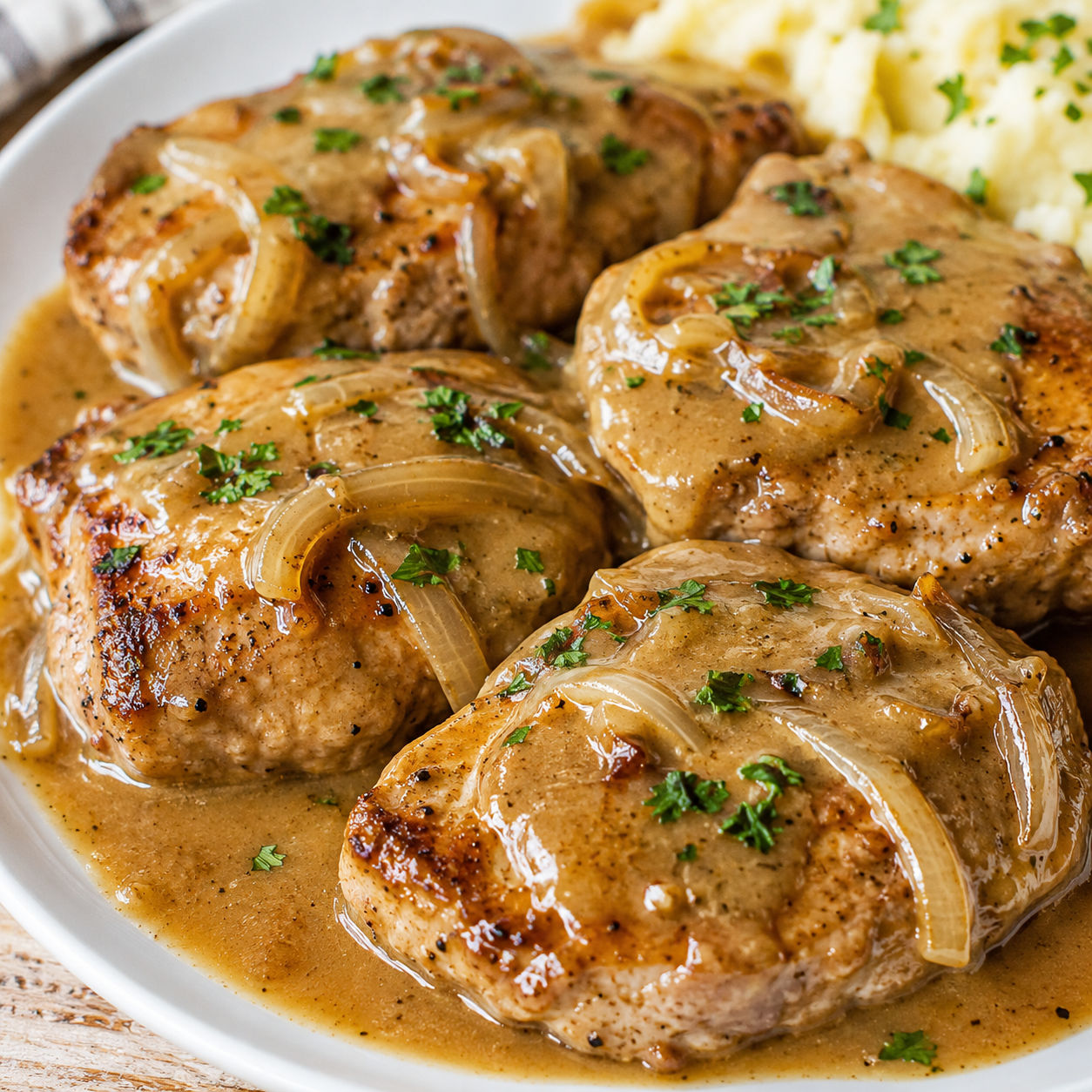 Smothered boneless pork chops with onion gravy and parsley