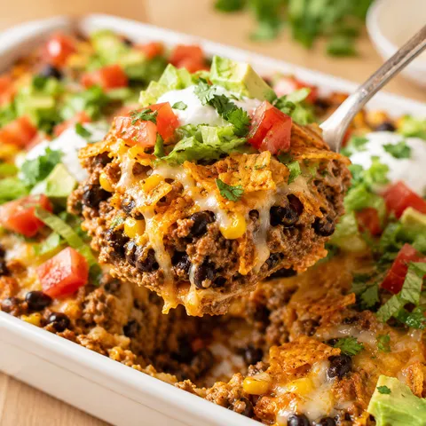 Doritos taco casserole with beef, melted cheese, tomatoes, and cilantro