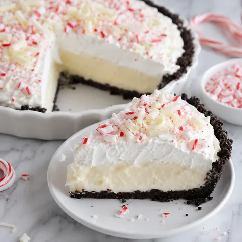 White chocolate peppermint pie slice with whipped cream and candy cane pieces