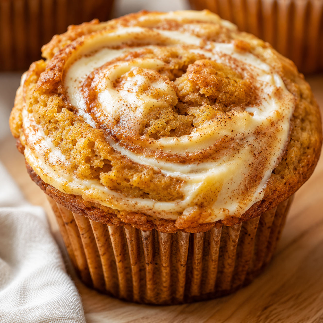 Fluffy pumpkin cream cheese swirl muffin with tall domed top and spice specks