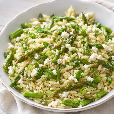 Fresh orzo with asparagus, feta, lemon, and herbs in a shallow bowl