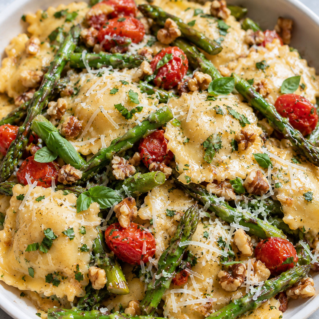 Cheese ravioli with asparagus, tomatoes, herbs, walnuts, and parmesan
