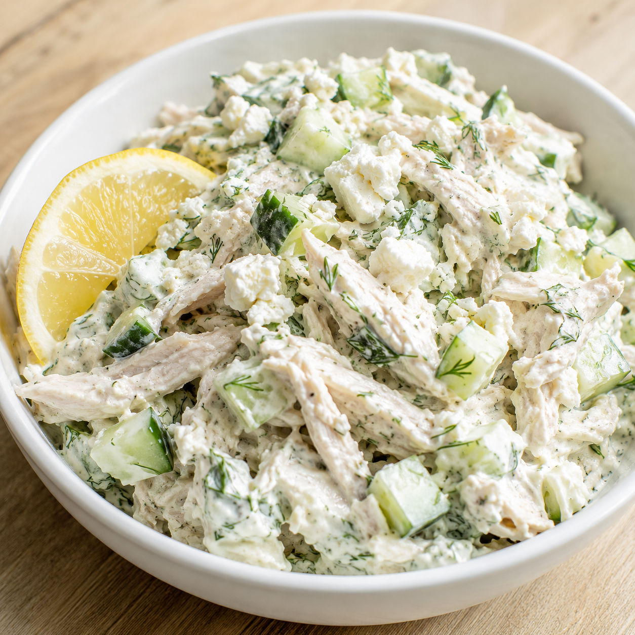 Creamy tzatziki chicken salad with dill, cucumber, and feta in a white bowl