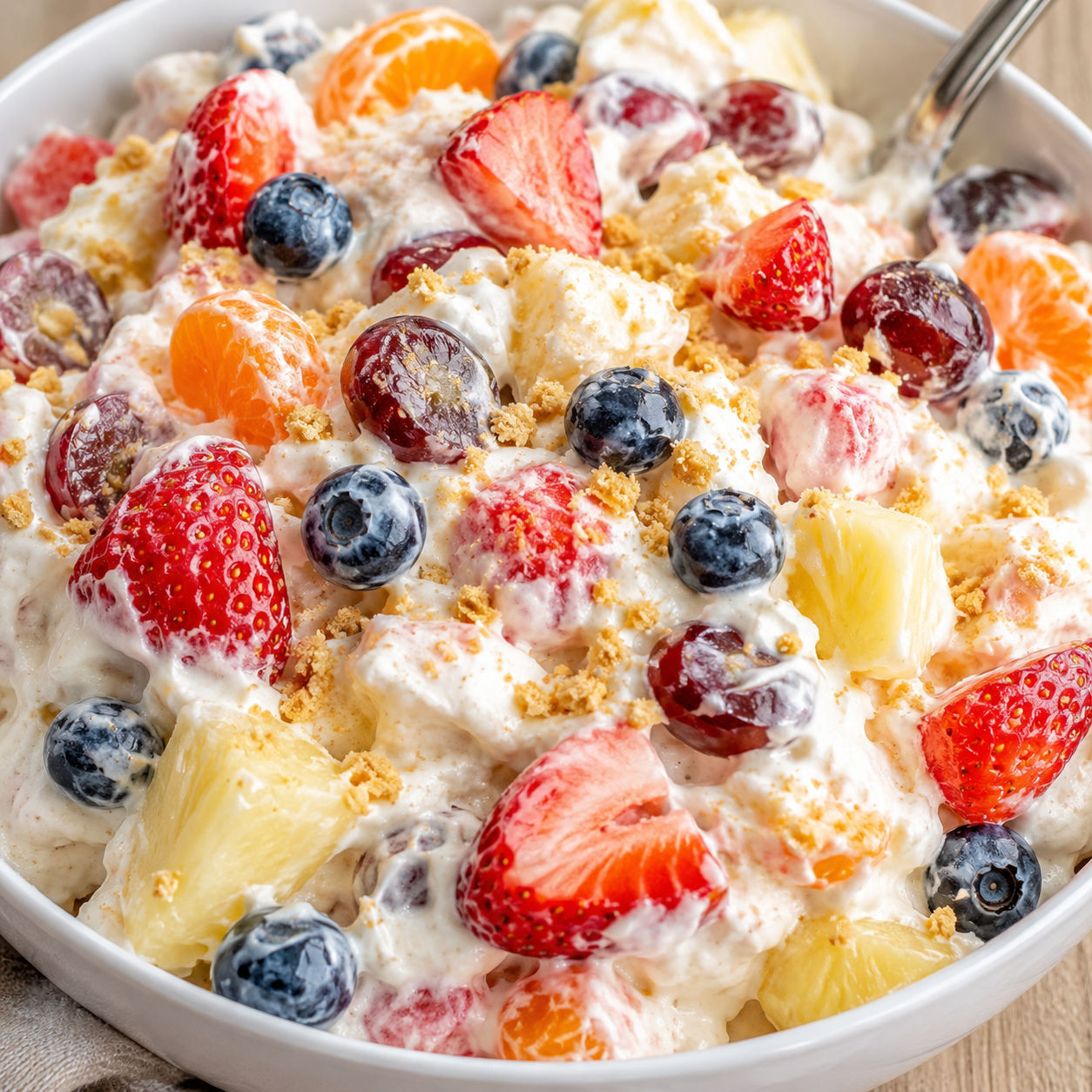 Fruit Salad Cheesecake with berries, grapes, pineapple, and graham crumbs