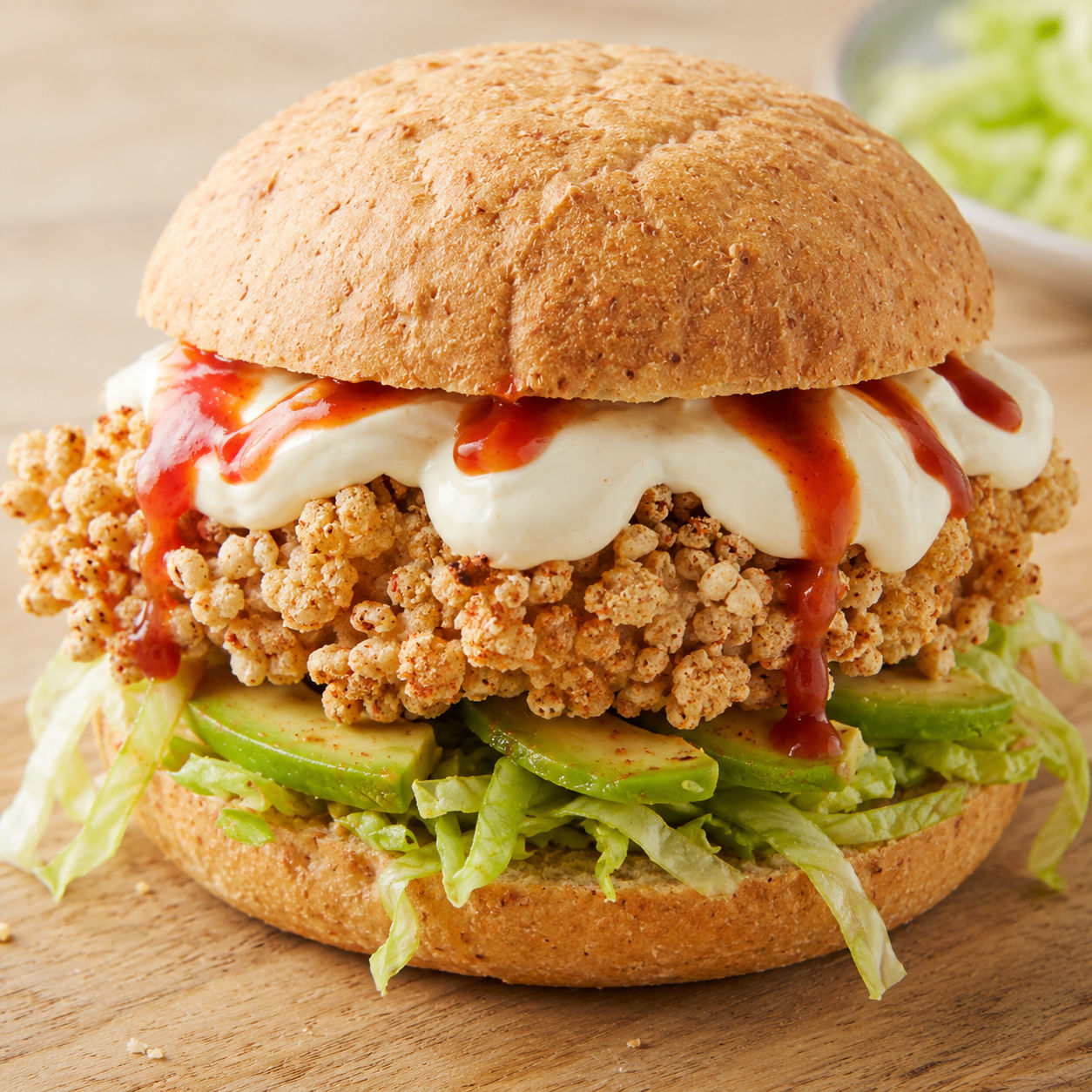 Crispy chicken sandwich with avocado, lettuce, yogurt dressing, and hot sauce