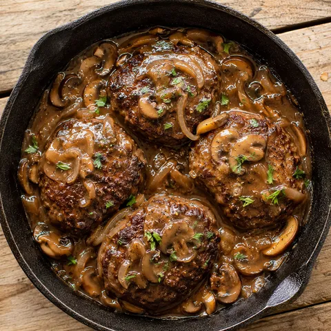 Hamburger steaks with mushroom gravy in a cast iron skillet