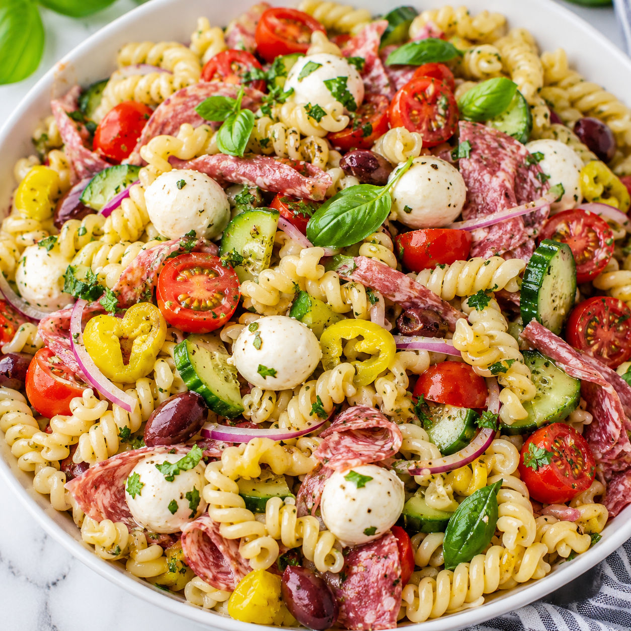 Italian pasta salad with fresh mozzarella, salami, tomatoes, olives, and basil