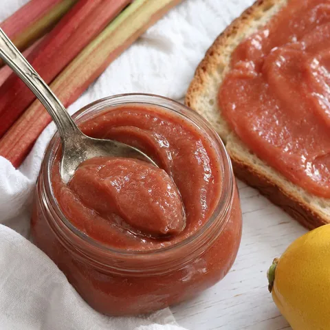 Sweet tangy rhubarb butter in a jar with toast and fresh rhubarb