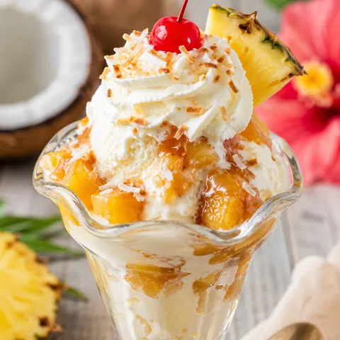 Piña colada ice cream sundae with pineapple, coconut, whipped cream, and cherry