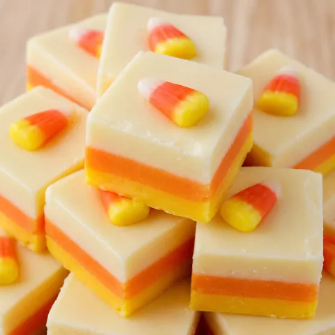 Stacked candy corn fudge squares with yellow orange and white layers