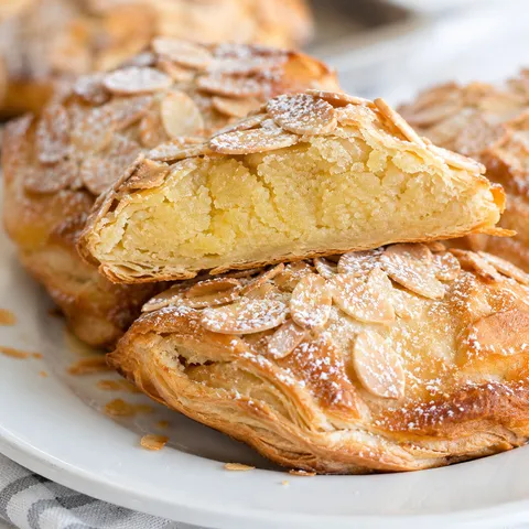 Flaky almond pastries with sliced almonds and powdered sugar