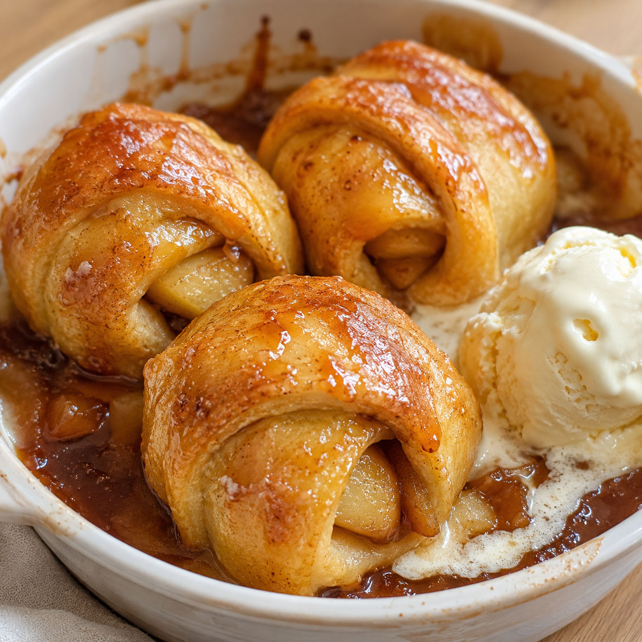 Golden baked apple dumplings in sticky caramel sauce with melting vanilla ice cream
