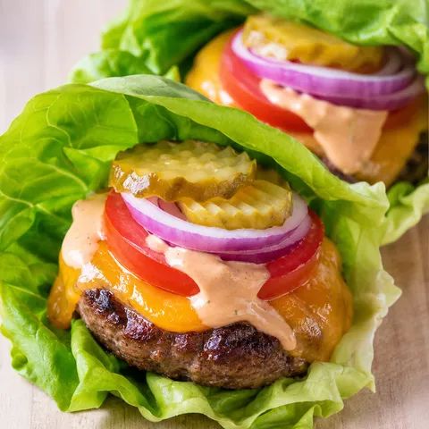Lettuce wrap burgers with beef patties, cheddar, tomato, pickles, and sauce