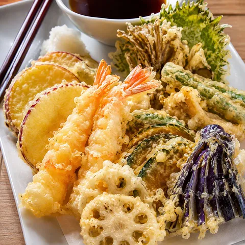 Shrimp and vegetable tempura with tentsuyu sauce on a white plate