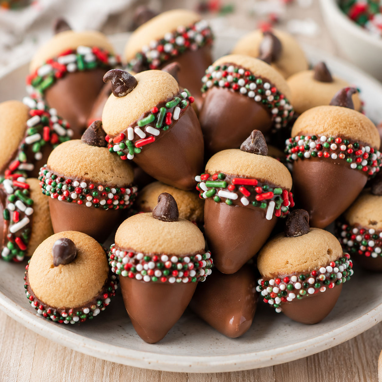 Festive chocolate candy acorns with sprinkle caps on a white ceramic plate