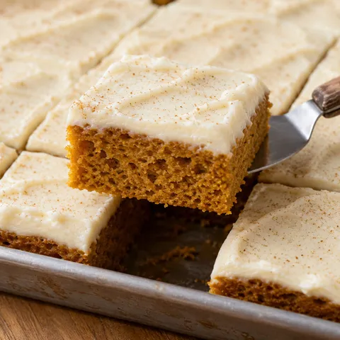 Pumpkin bars with cream cheese frosting and cinnamon in a metal pan