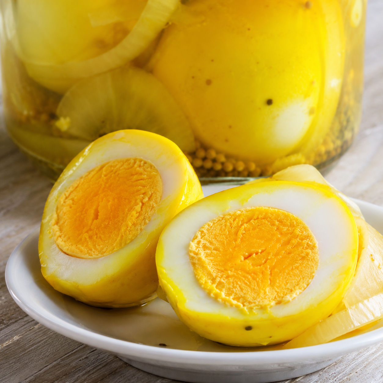 Halved mustard pickled egg with bright golden yolk on a white plate