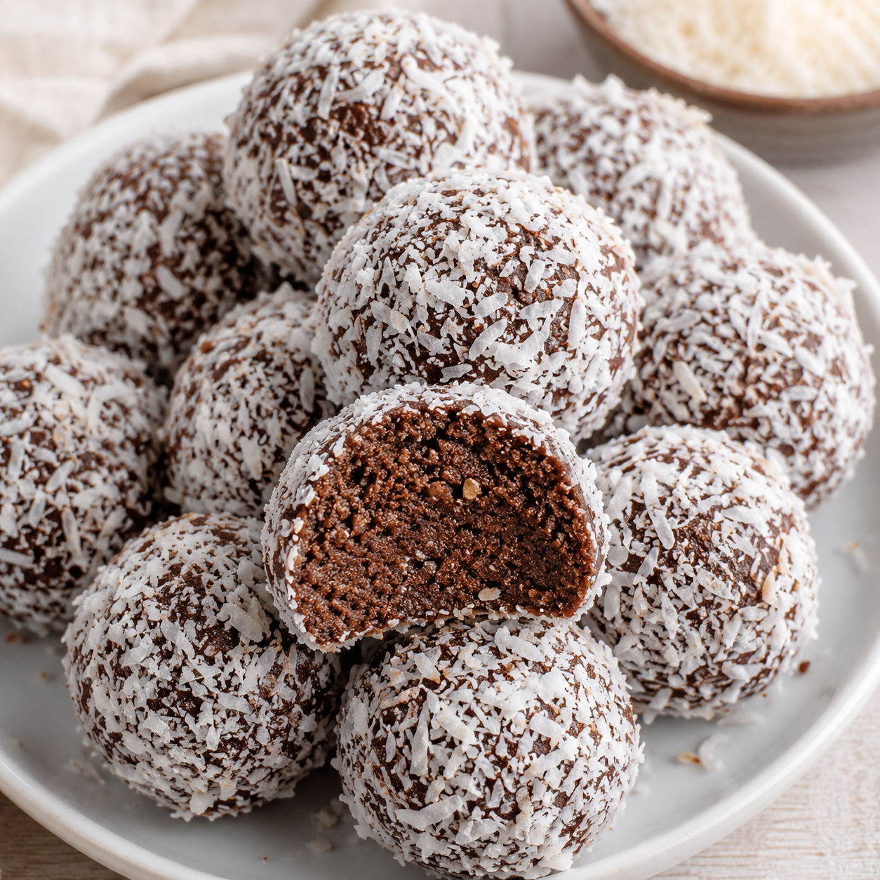 Chocolate coconut graham balls coated in shredded coconut on a white plate