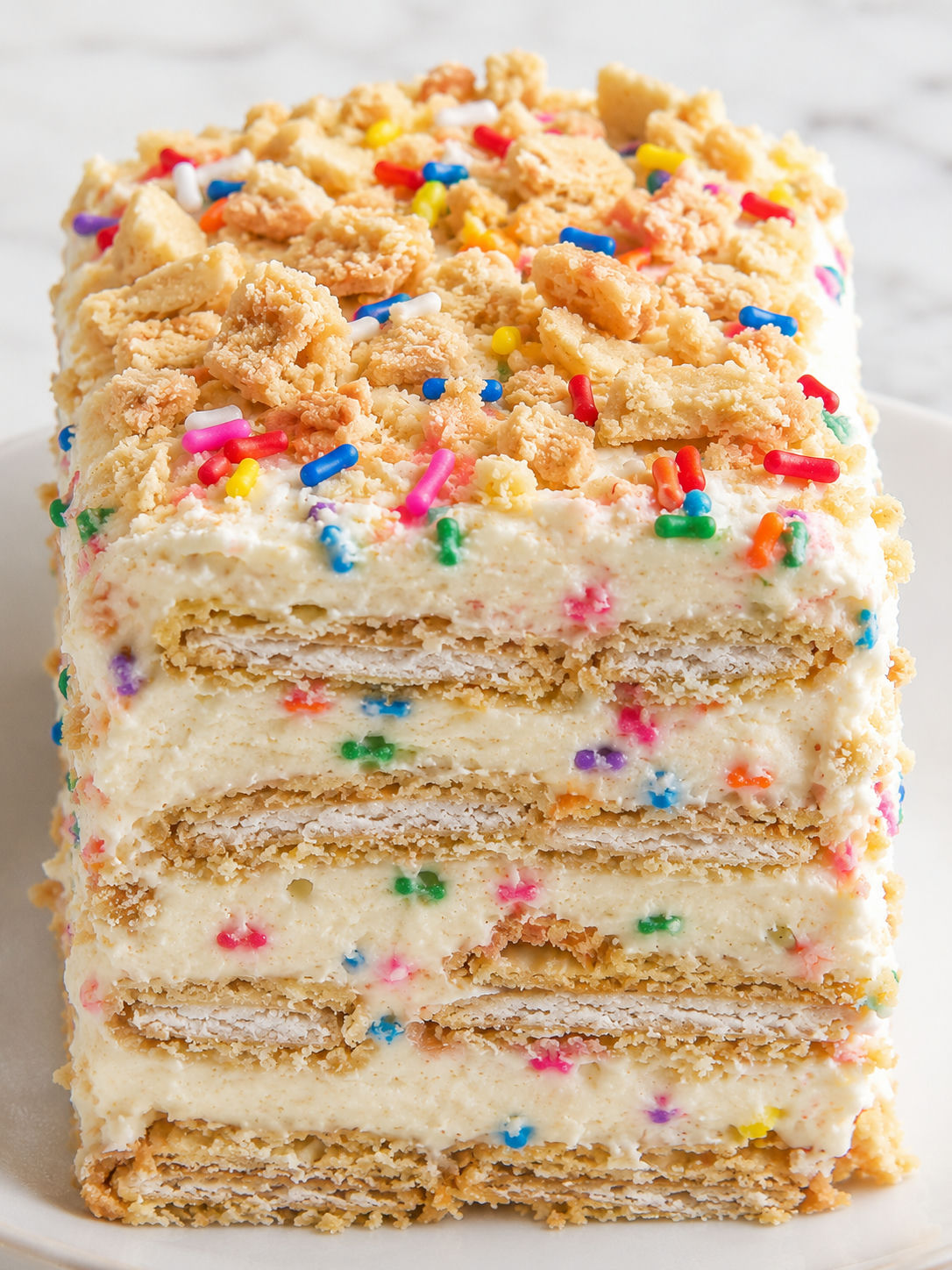Tall slice of funfetti Oreo icebox cake with sprinkles and cookie crumbs