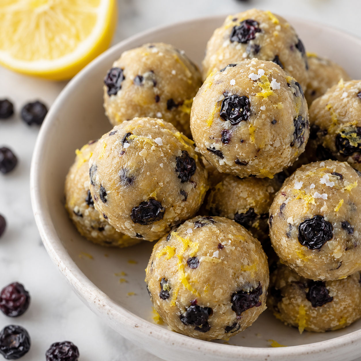 Lemon blueberry protein bites in a white bowl with lemon zest