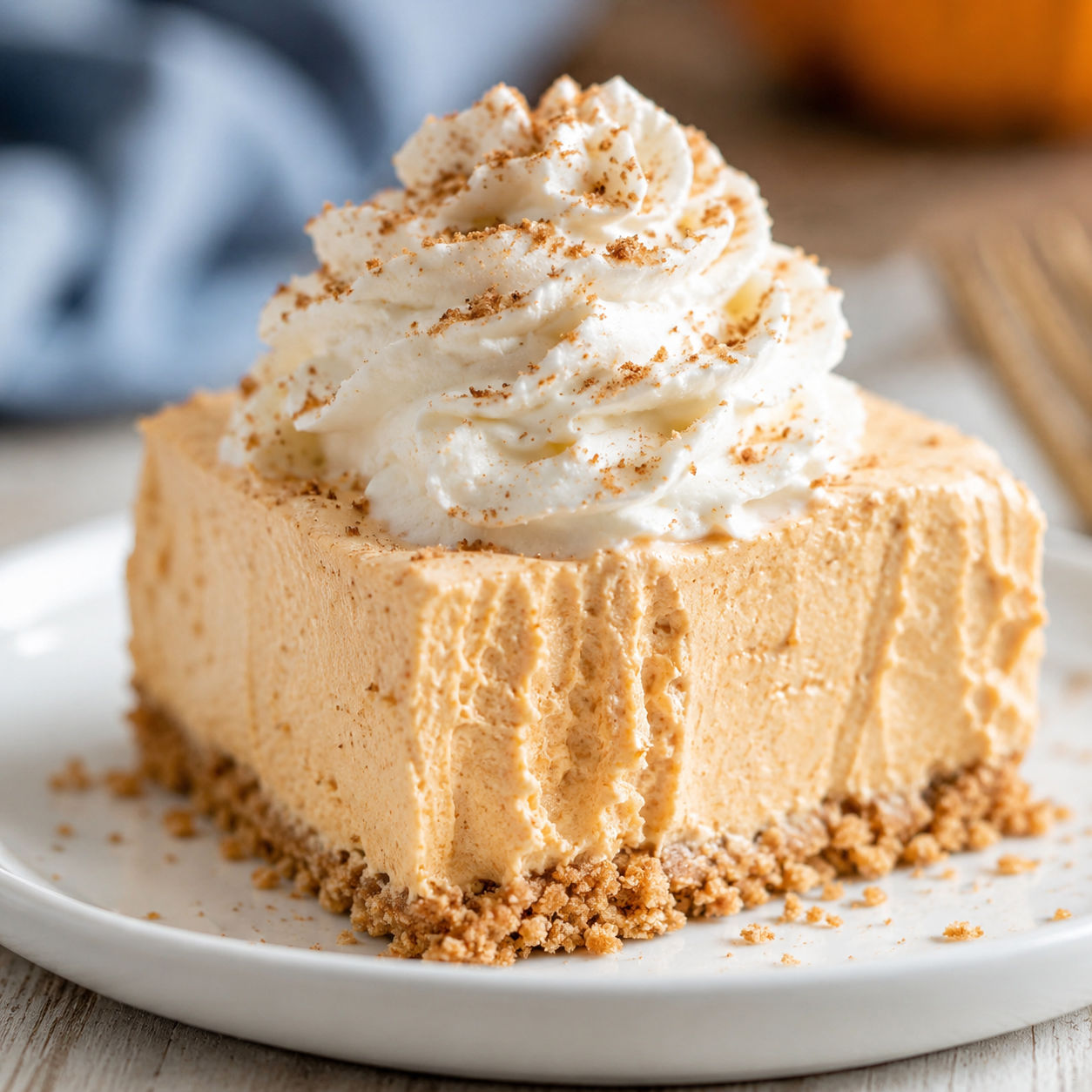 Slice of no bake pumpkin cheesecake with whipped cream and cinnamon dust