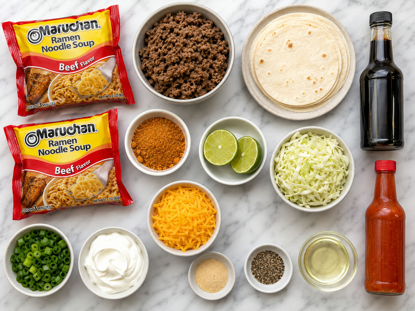 Ingredients for ramen noodle tacos with beef, tortillas, cabbage, cheese, and lime