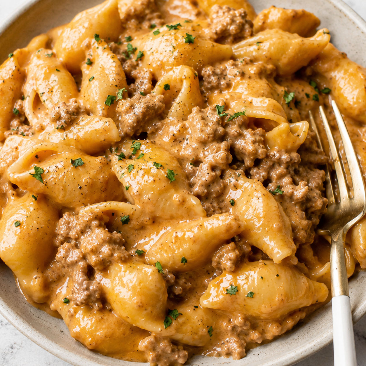 Cheesy beef and shells with parsley in a shallow bowl