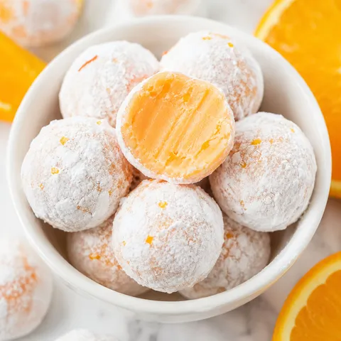 Orange creamsicle truffles with powdered sugar and fresh orange slices