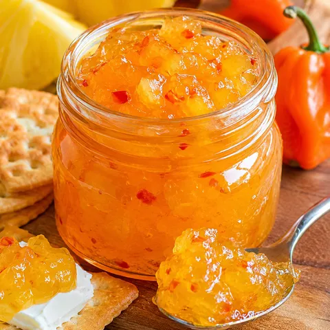Golden pineapple habanero pepper jelly in a jar with crackers