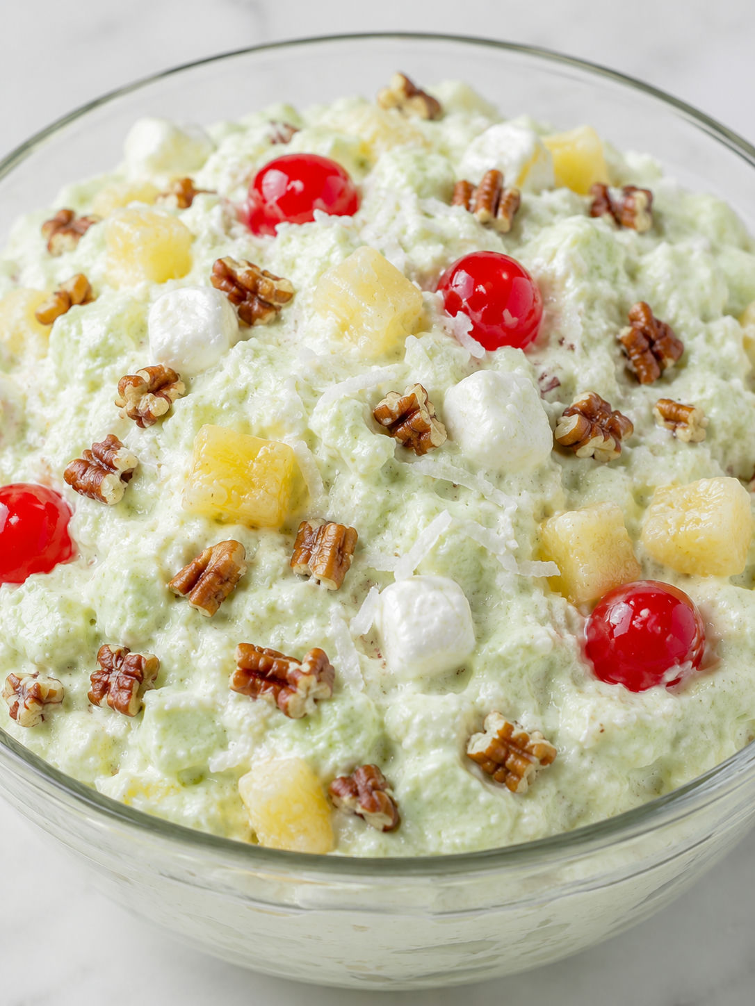 Creamy pistachio pineapple fluff topped with pecans and cherries