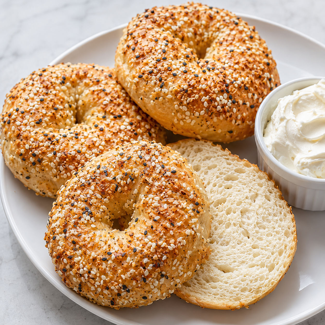 Golden cottage cheese protein bagels with everything seasoning on a white plate