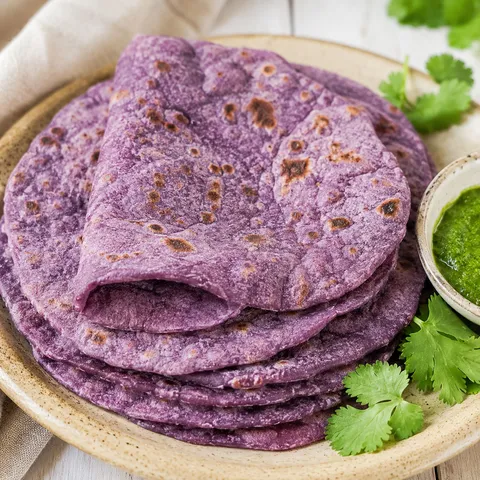 Purple sweet potato roti stacked with green chutney and cilantro