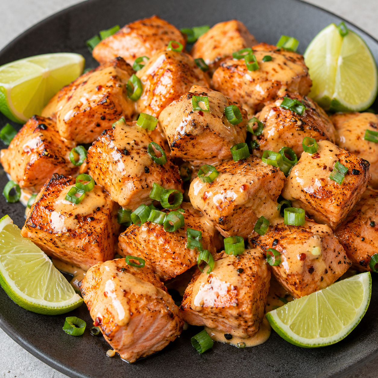 Bang bang salmon bites with creamy sauce, green onions, and lime