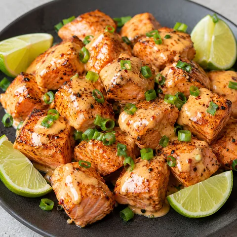 Bang bang salmon bites with creamy sauce, green onions, and lime