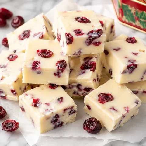 White chocolate cranberry fudge squares with dried cranberries on parchment