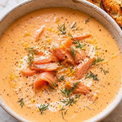 Creamy smoked salmon bisque with dill and lemon zest in a ceramic bowl