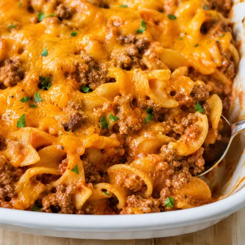 Ground beef and noodle casserole with melted cheddar and parsley