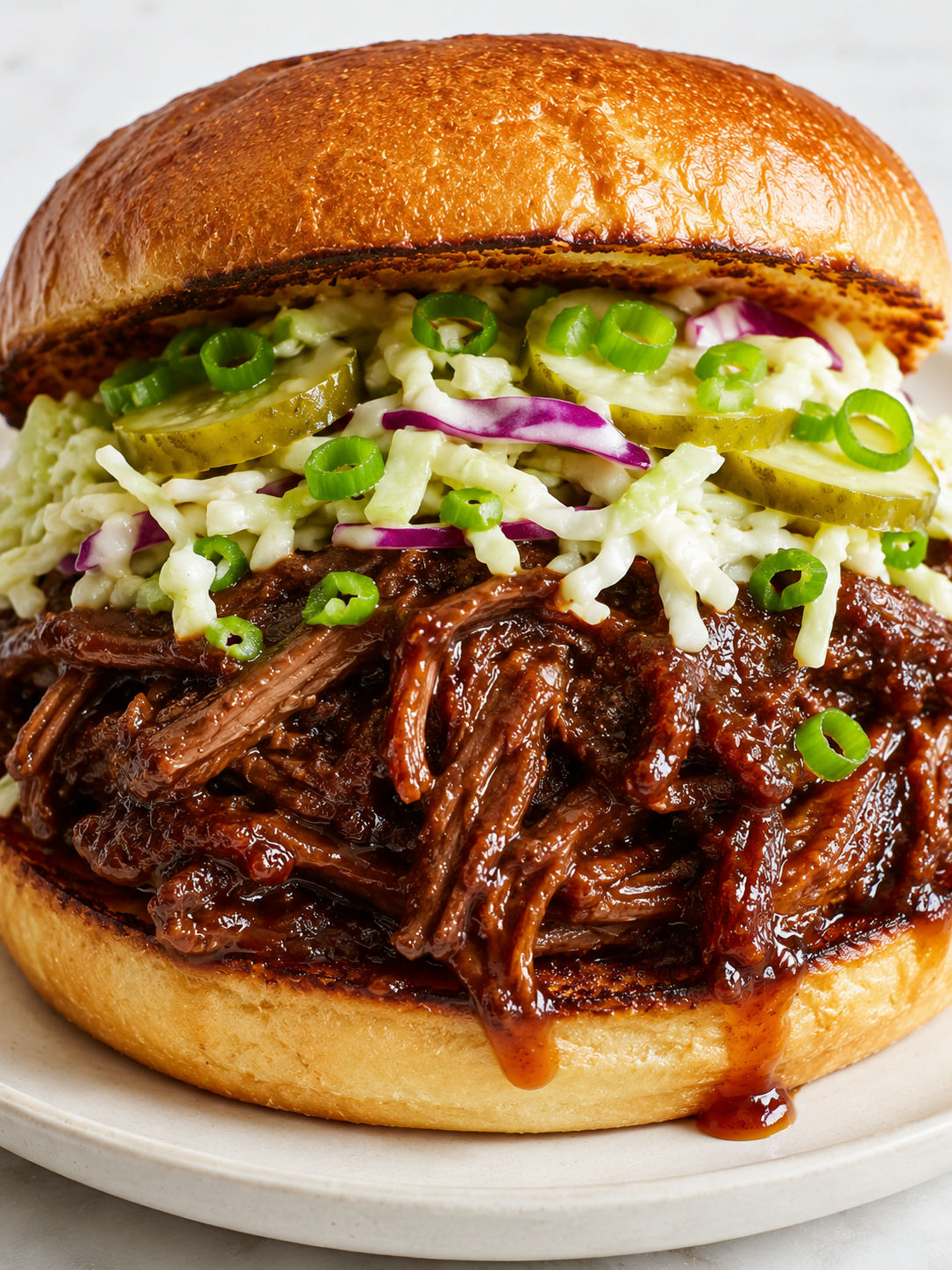Tall spicy ginger ale shredded beef sandwich with glossy glaze and slaw