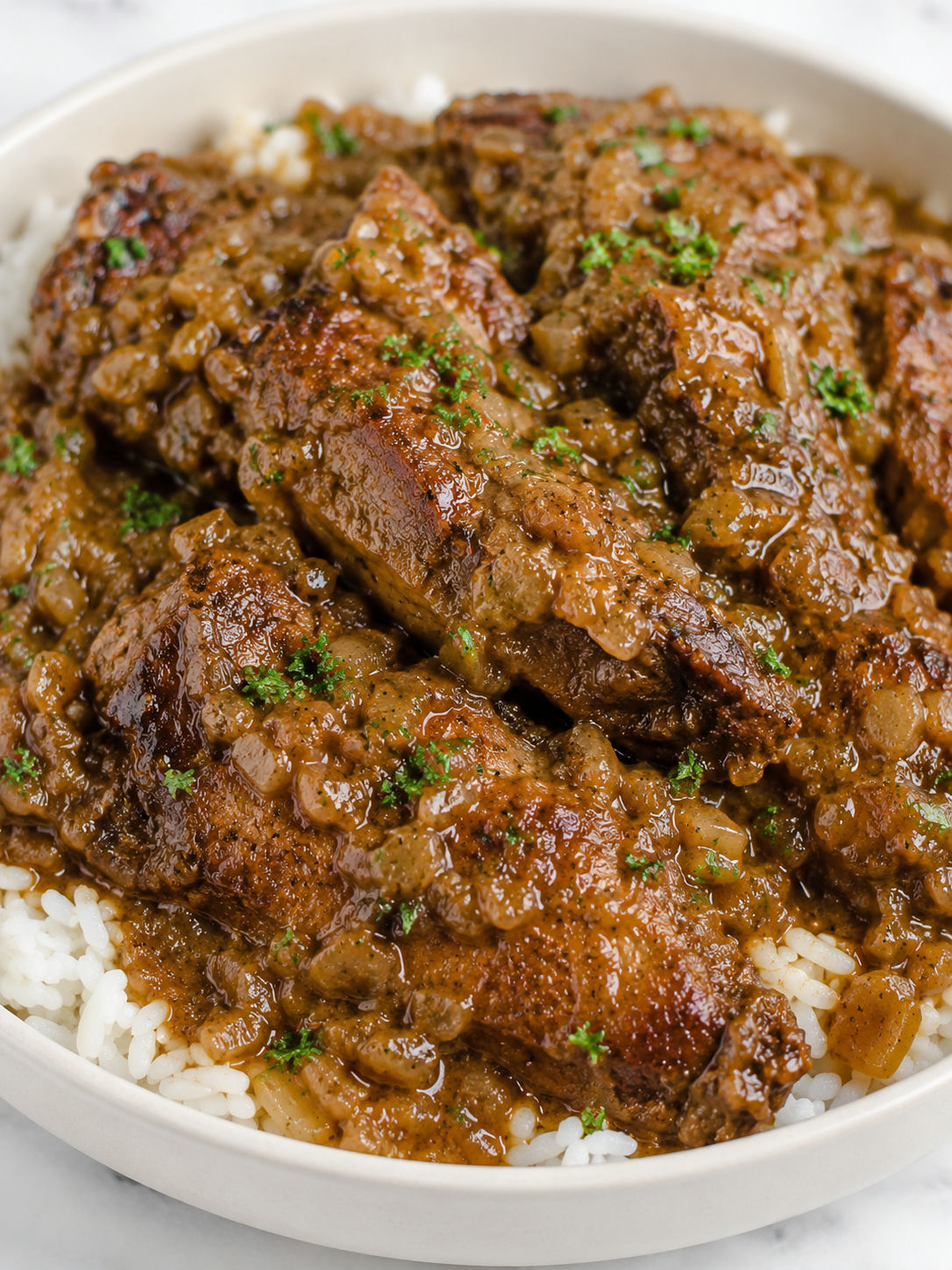 Tender smothered turkey wings in glossy onion gravy over rice