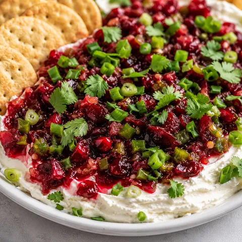 Cranberry jalapeno cream cheese dip with crackers and green garnish
