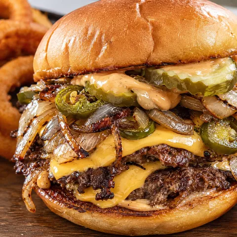 Spicy jalapeño-onion smash burger with melted cheese and pickles