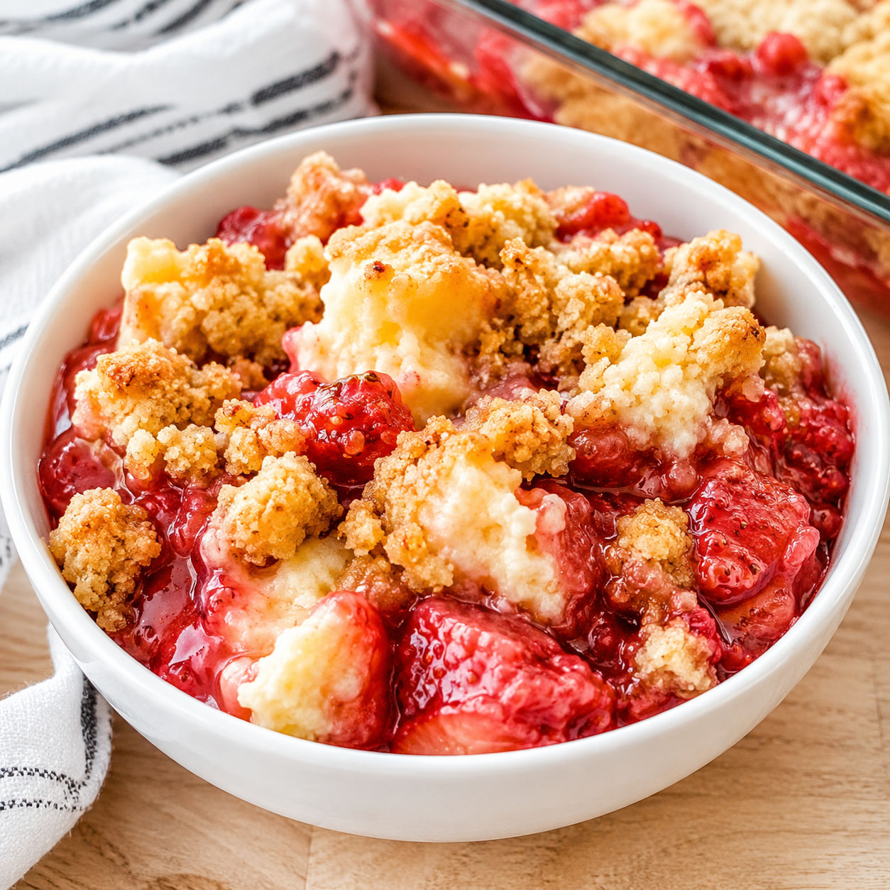 Strawberry cheesecake dump cake with golden topping in a white bowl